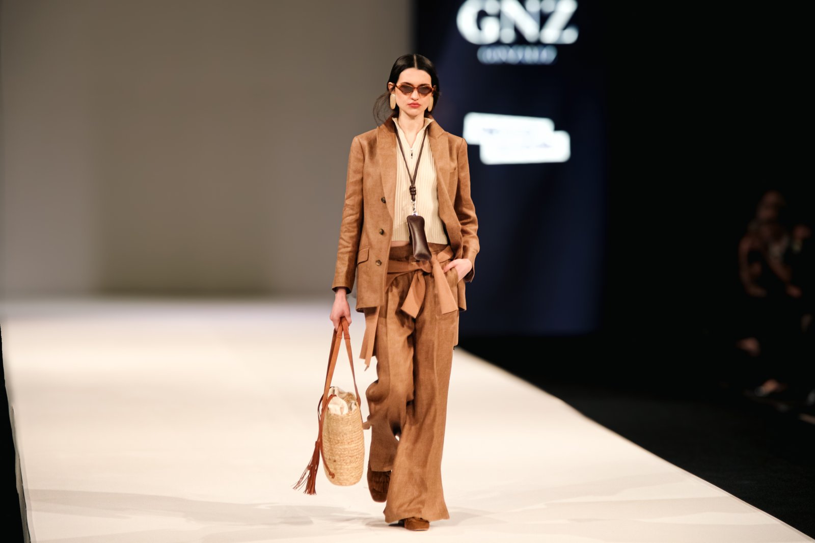 Modelo en pasarela con look camel sobre fondo GNZ